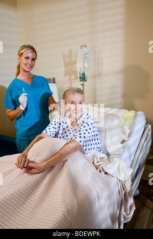 Donna anziana nel letto di ospedale con un infermiere tenendo la siringa Foto Stock