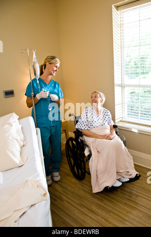 Infermiera e donna senior in sedia a rotelle in camera di ospedale Foto Stock