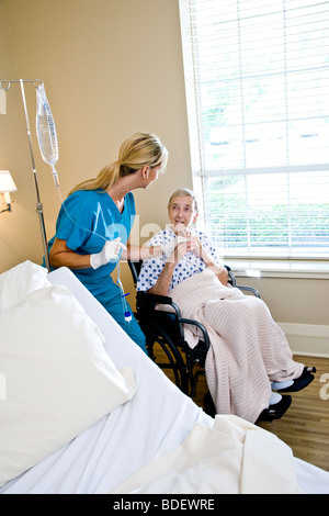 Infermiera e donna senior in sedia a rotelle in camera di ospedale Foto Stock