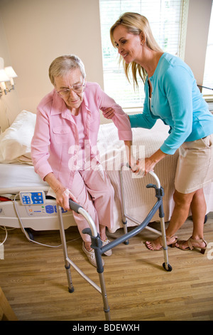 Figlia adulta aiutando madre anziana utilizzare walker Foto Stock