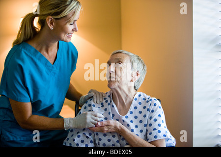 Donna anziana in carrozzina getting medicina da un infermiere Foto Stock