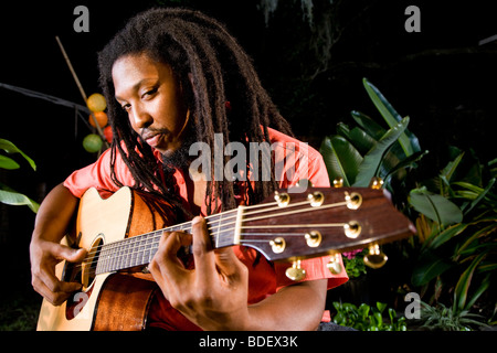 Giovane uomo giamaicano con dreadlocks a suonare la chitarra Foto Stock