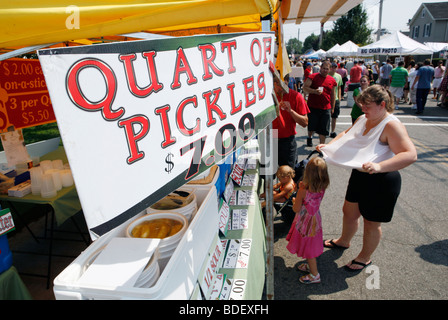 Una donna fan se stessa nel calore ad un'estate street fair, Long Island, New York Foto Stock