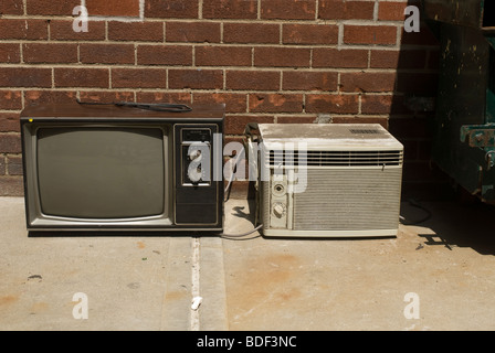 Un scartato apparecchio televisivo analogico e il condizionatore d'aria in attesa di prelievo da parte del dipartimento di igiene in New York Foto Stock