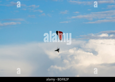 Un powered pilota di parapendio in volo con un cielo nuvoloso in background Foto Stock