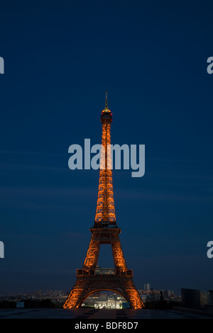 La torre Eiffel di notte illuminata con incandescente luci di colore arancione, luci della città al di sotto, twilight sfondo cielo, dal Trocadero Parigi 14 luglio 2009 Foto Stock