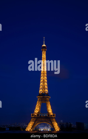 Calde luci incandescenti sulla torre Eiffel con belle blu profondo cielo crepuscolo sfondo, luci della città al di sotto, famoso monumento nazionale di Parigi, Francia Foto Stock