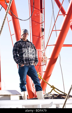 Giovane pescatore in plaid shirt permanente sulla barca da pesca Foto Stock