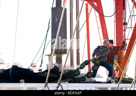 I giovani pescatori in plaid shirt tirando reti sulla barca da pesca Foto Stock