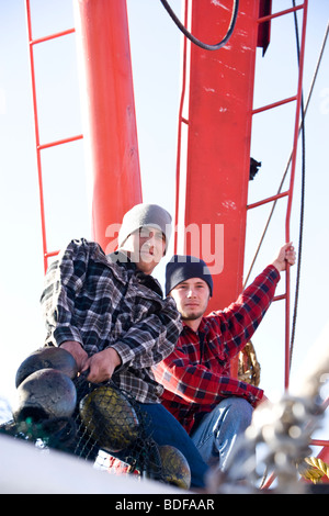 I giovani pescatori in plaid shirt tirando reti sulla barca da pesca Foto Stock