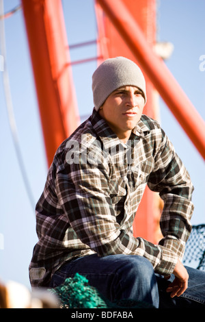 Giovane pescatore in plaid shirt seduto sulla barca da pesca Foto Stock