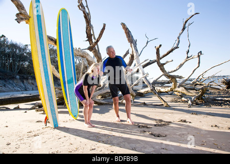 Di mezza età matura nella muta sulla spiaggia con tavole da surf Foto Stock