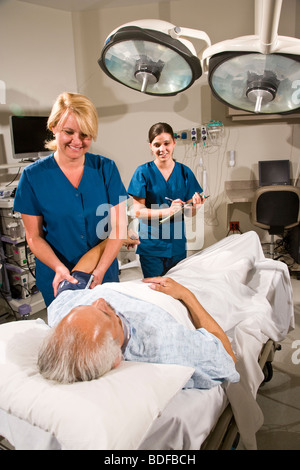 Gli infermieri tenendo la pressione del sangue del paziente nella stanza di ospedale Foto Stock