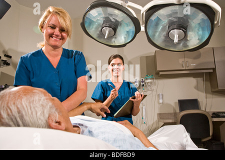 Gli infermieri tenendo la pressione del sangue del paziente nella stanza di ospedale Foto Stock