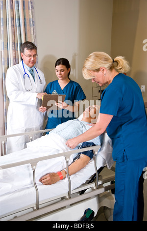 Medico e infermiere in ospedale recovery room con paziente Foto Stock