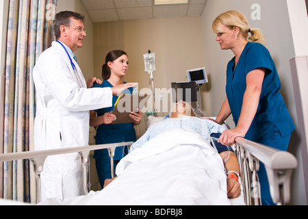 Medico e infermiere in ospedale recovery room con paziente Foto Stock