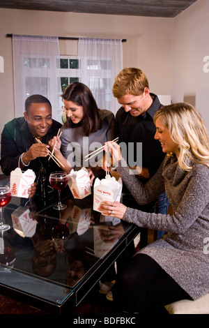 Multi-etnico coppie di mangiare il cinese take-out nei moderni loft Foto Stock