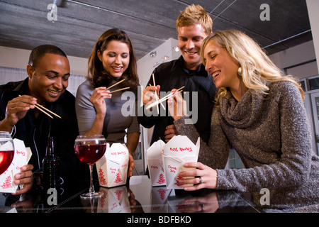 Multi-etnico coppie di mangiare il cinese take-out nei moderni loft Foto Stock