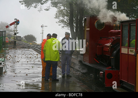 Una conversazione tra driver, vigili del fuoco e la guardia a Woody Bay stazione sul Lynton & Barnstaple Railway, Devon, Inghilterra, Regno Unito Foto Stock