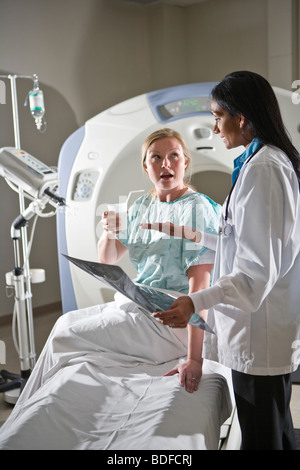 Medico rivedendo CT i risultati di scansione con paziente Foto Stock