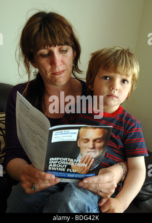 "Influenza suina foglietto' "influenza suina" La donna la lettura del "influenza suina" foglietto con suo figlio Foto Stock