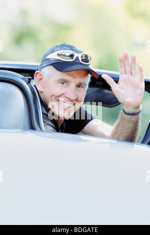 Ritratto di un uomo anziano sventolando nella sua cabriolet Foto Stock