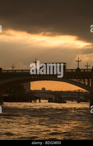 Double Decker inglese bus rosso passando Thames bridge al tramonto Londra Inghilterra Europa nuvoloso meteo raggi di luce Foto Stock