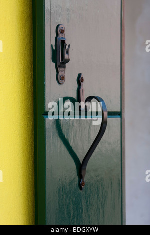 Vivacemente colorato di giallo e persiane verdi a forma di cuore bloccare la riflessione sulla casa di Burano, Venezia Veneto, Italia Foto Stock