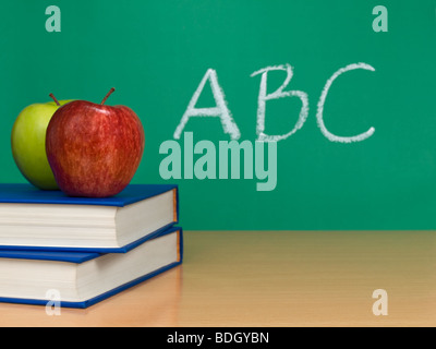 ABC scritto su una lavagna. Due mele su libri in primo piano. Foto Stock