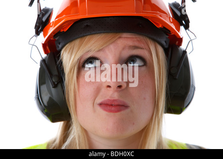 I giovani di 20 anni donna bionda cercando confuso arancione da indossare elmetto otoprotettori visiera e alta vis vest Foto Stock