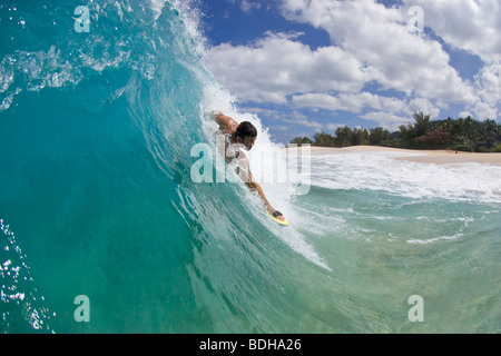 Un giovane uomo body surfing a Keiki spiaggia sulla costa nord di Oahu, Hawaii. Foto Stock