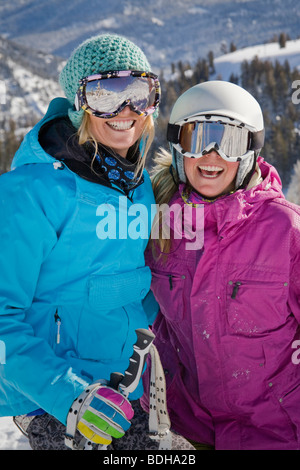 Due donne gli sciatori in caschi sorridente e divertimento sulle piste da sci. Foto Stock