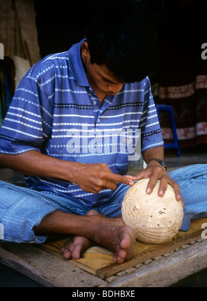 Indonesia, Bali, artigianato, uomo carving guscio di noce di cocco Foto Stock