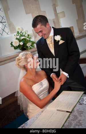 Sposa e lo sposo firma registro nella chiesa sulla Chiesa in Inghilterra Foto Stock