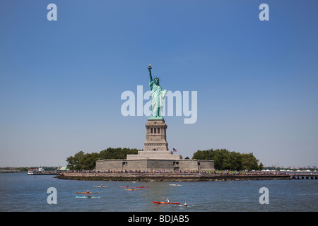 Statua della Libertà testimoni un kayak racing lungo il fiume Hudson, New York City, Stati Uniti d'America. Foto Stock