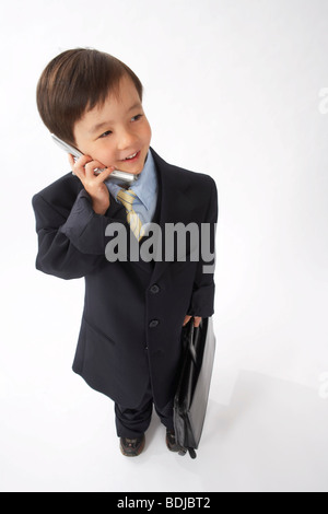 Little Boy vestito come un imprenditore parlando al cellulare Foto Stock