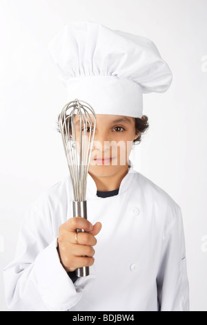 Ragazzo vestito come un cuoco tenendo una frusta Foto Stock