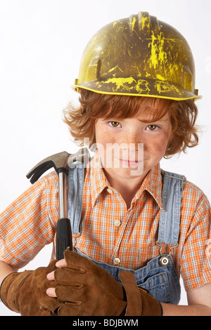 Little Boy vestito come operaio edile tenendo un martello Foto Stock