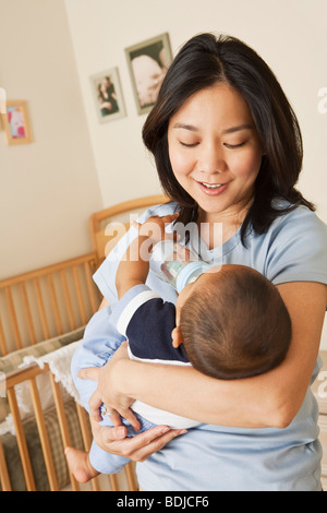 Azienda madre Baby Boy mentre egli è bere dal biberon Foto Stock