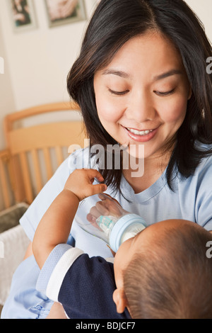 Azienda madre Baby Boy mentre egli è bere dal biberon Foto Stock