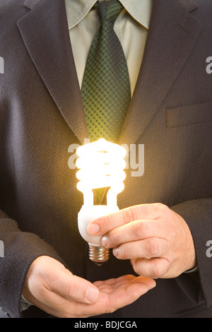 Imprenditore tenendo accesa lampadina a basso consumo Foto Stock