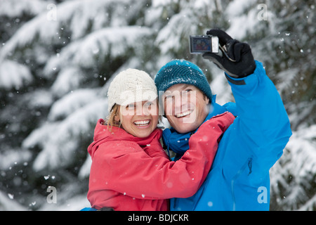 Giovane tenendo Autoritratto con la fotocamera del telefono all'aperto in inverno, Whistler, British Columbia, Canada Foto Stock