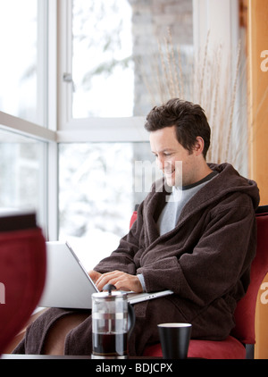 Uomo in accappatoio utilizzando il computer portatile Foto Stock