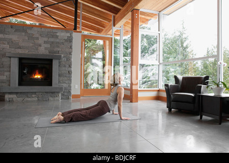 Donna facendo Yoga nel salotto della grande casa alpina Foto Stock