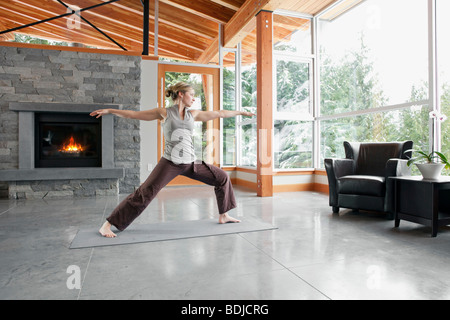 Donna facendo Yoga nel salotto della grande casa alpina Foto Stock