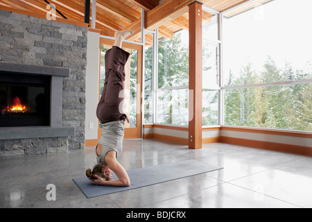 Donna facendo Yoga nel salotto della grande casa alpina Foto Stock