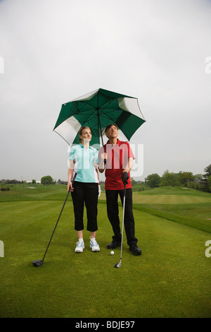 Padre e figlia sul campo da golf tenendo un grande ombrellone Foto Stock