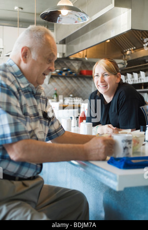 Uomo in Coffee Shop in chat con cameriera Foto Stock