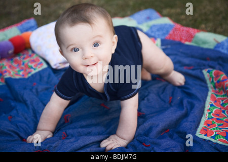 Il bambino gioca su una coperta al di fuori Foto Stock