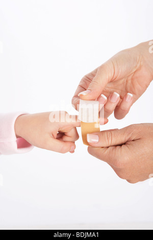 Mom mettendo Bandaid su figlia del dito Foto Stock